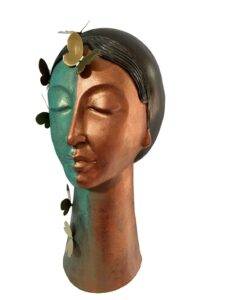 Maya 5 — mixed media head sculpture by Romicon Revola with split teal and copper two-tone surface finish, etched hair detail, elongated neck base and brass butterfly elements, side view.