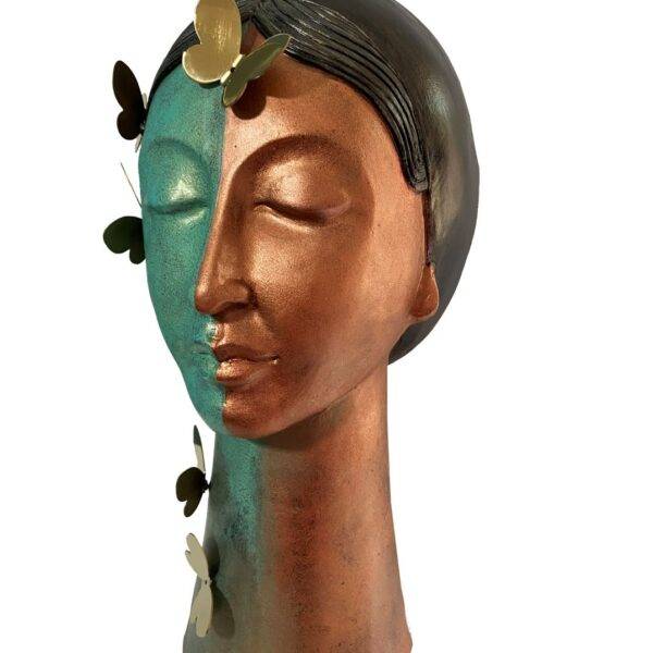 Maya 5 — mixed media head sculpture by Romicon Revola with split teal and copper two-tone surface finish, etched hair detail, elongated neck base and brass butterfly elements, side view.